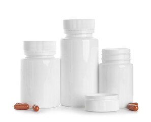 Blank plastic vitamin bottles and orange pills on white background