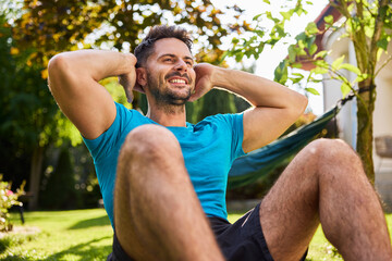 Handsome man doing sit-ups  in the backyard garden