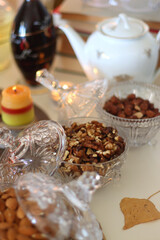 Lit candles, cookies, chocolate, nuts, tea, wine, pumpkins, books, reading glasses and autumn leaves on the table. Autumnal hygge at home. Selective focus.