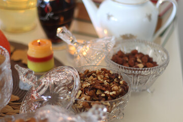 Lit candles, cookies, chocolate, nuts, tea, wine, pumpkins, books, reading glasses and autumn leaves on the table. Autumnal hygge at home. Selective focus.