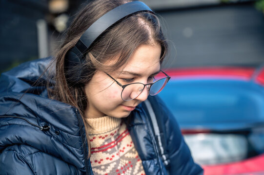 Smiling teenager girl with braces, eyeglasses and headphones - Powered by Adobe
