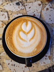 Tampilan atas secangkir kopi latte dengan seni busa susu yang indah di atas meja marmer, konsep kafe pagi