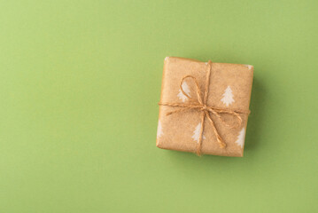 A Christmas gift wrapped in eco-friendly packaging on a green background