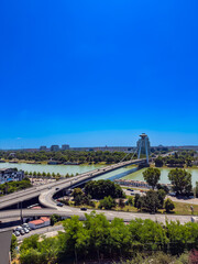 UFO Bridge and Danube view from hill in Bratislava. Wide view of Bratislava UFO Bridge crossing Danube River under bright blue sky.