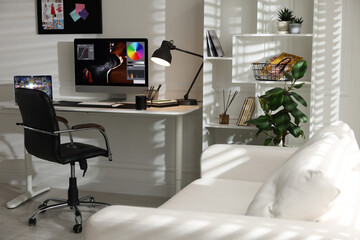 Stylish workplace with computer, laptop, cup, stationery and mat on desk indoors