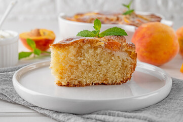 Delicious peach pie in a white ceramic baking form on a white wooden background. Summer cake. Selective focus, copy space.