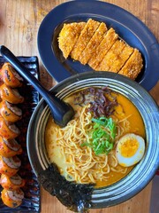 Japanese ramen with rich broth, soft-boiled egg, and seaweed served alongside crispy katsu and spicy sushi rolls. A vibrant Asian meal representing flavor, comfort, and culinary craftsmanship.