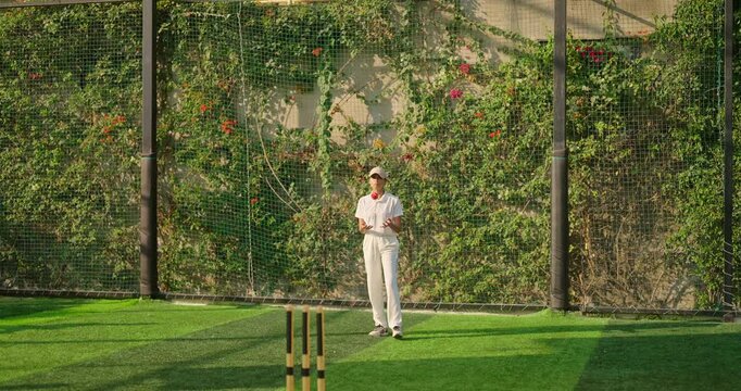 Indian young adult gen z bowler woman lady standing at match ground wear white uniform with cap. Asian teen age female girl running play cricket learn game do practice to hit wicket throw ball place - Powered by Adobe