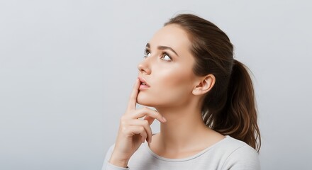 Young woman covering mouth lightly with fingers in a “hmm” gesture
