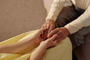 Senior Caucasian man gently holding hands of young adult Caucasian woman, showing intergenerational connection and support, close up of hands emphasizing age difference and tenderness
