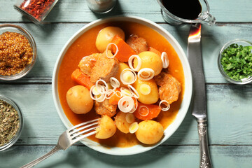 Baking dish of tasty beef stew with onion, spices, mustard and soy sauce on wooden background