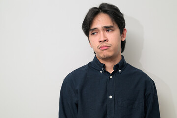 Fototapeta premium Portrait of handsome Young Asian Thai man looking sad while thinking against white background