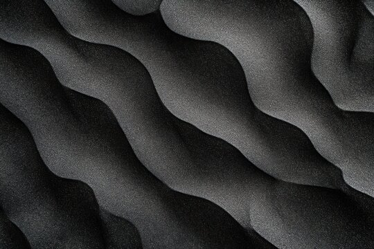 Close-up abstract view of layered black sand dunes with smooth flowing curves and fine textured grains creating a natural wavy pattern