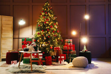 Decorated Christmas tree with many gifts and glowing lamps in living room at night