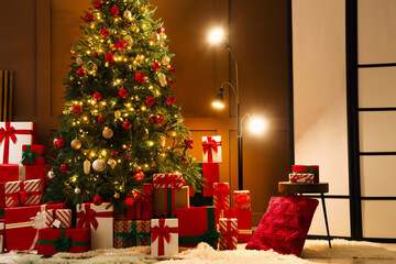 Decorated Christmas tree with many gifts, glowing lamp and folding screen in living room at night
