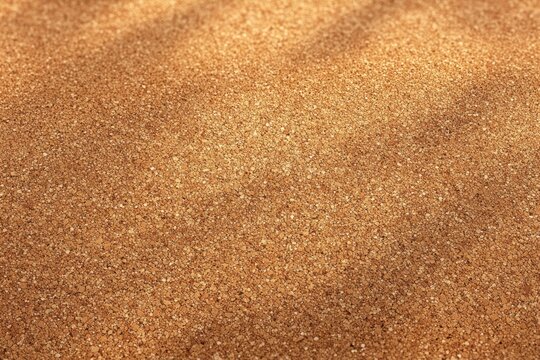 Close-up image of a textured golden sand surface with soft shadows and slight unevenness