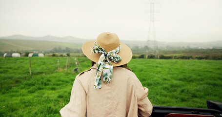 Travel, back and person on field with view, agriculture and scenery on holiday trip. Tourism, mountain and tourist in countryside with hat, farming vacation and outdoor journey in rural getaway.