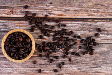 Coffee beans in a wooden cup against a wooden table background.