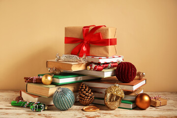Books with Christmas balls and gift boxes on white wooden table against beige background