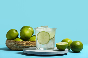 Decorative podium with glass of lime infused water on blue background