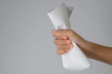 Hand holding crumpled white paper tightly on grey background
