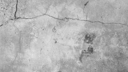 Aged gray concrete wall with visible cracks and peeling paint. Weathered and broken surface texture...
