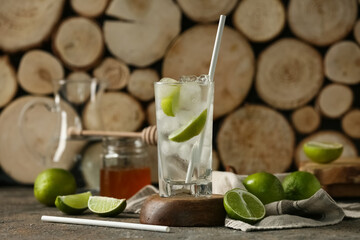 Glass of lime infused water and jar of honey on dark table
