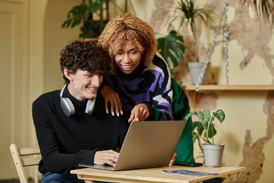 Stylish couple enjoying time together in a cozy cafe while working on a laptop