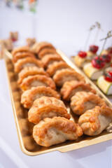 Golden fried dumplings arranged on elegant gold tray at luxury catering event