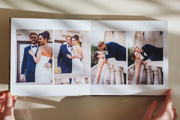 Female hands flipping through a photo book with wedding photos on a white table