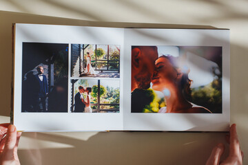 Female hands flipping through a photo book with wedding photos on a white table