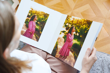 woman is holding and flipping through a photo book with a pregnancy photo shoot