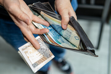 Person taking out a 200 Polish złoty banknote from a wallet full of cash. Financial transaction, personal budgeting