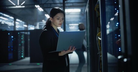 Female Administrator Working on Laptop in Data Center. - Powered by Adobe