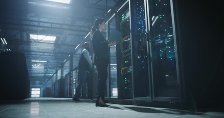 Administrator with a laptop inspects server racks in a data center, checking optimal functioning of network.  - Powered by Adobe