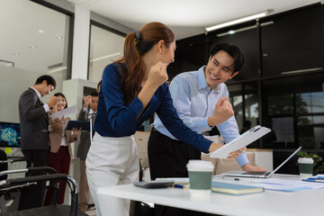 Obraz premium Successful business team, excited young people Keeping up arms and showing positive emotions, happy working in modern office on computer.