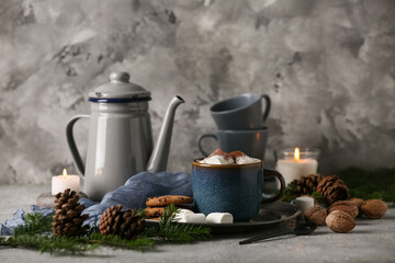 Cup of hot chocolate with marshmallows, cookies and winter decor on grey grunge background