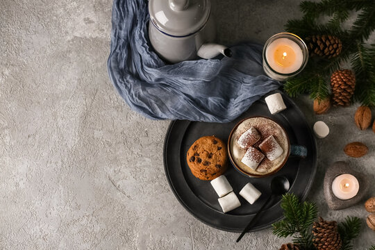 Cup of hot chocolate with marshmallows, cookies and winter decor on grey grunge background