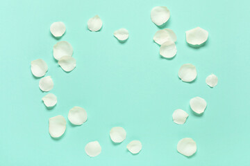 Frame made of beautiful white rose petals on turquoise background
