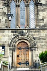 Historic Stone Church Entrance with Gothic Windows and Wooden Door