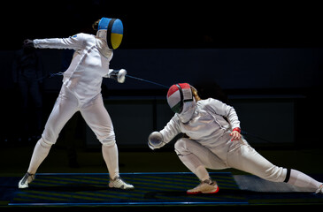 Two female fencing athletes fighting