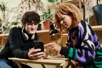 Stylish couple enjoy a cozy moment in a trendy cafe, sharing laughter and discovering something new