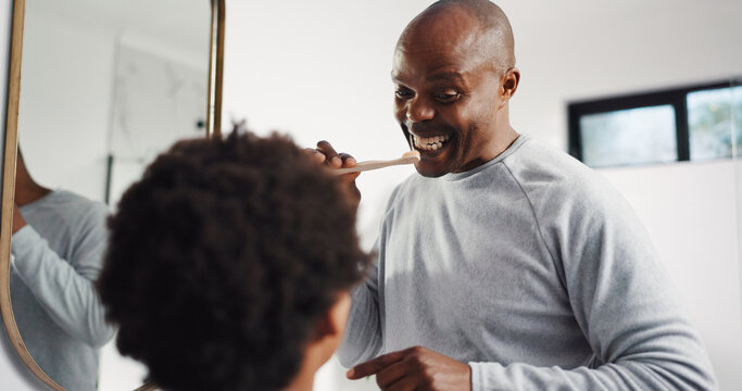 Teaching, brushing teeth and father with kid in bathroom in home for dental care, hygiene or wellness. Learning, oral health and African dad with boy child for mouth routine in morning together.