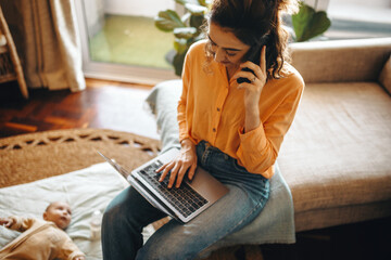 Working mom on laptop while talking on phone at home