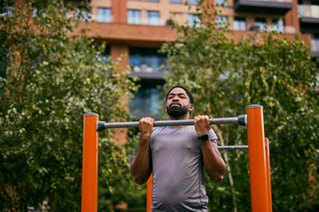 Obraz premium Everyday African Man Sets Weight Loss Goal With Outdoor Pull-Up Workout