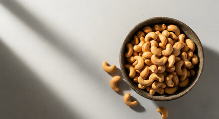 Bowl of roasted cashew nuts on speckled light surface
