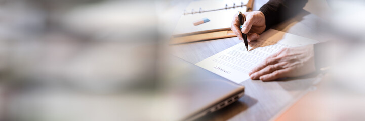 Senior businessman reviewing terms of contract; panoramic banner