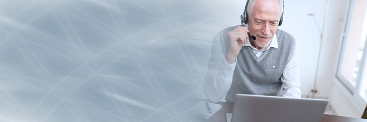 Businessman talking on a headset and using a laptop; panoramic banner