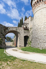 Obraz premium Entrance section of Brescia Castle showing ancient drawbridge near Torre dei Prigionieri, with stone arches, limestone walls, and traces of medieval defense engineering