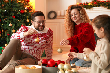 Happy family with ornaments near Christmas tree at home
